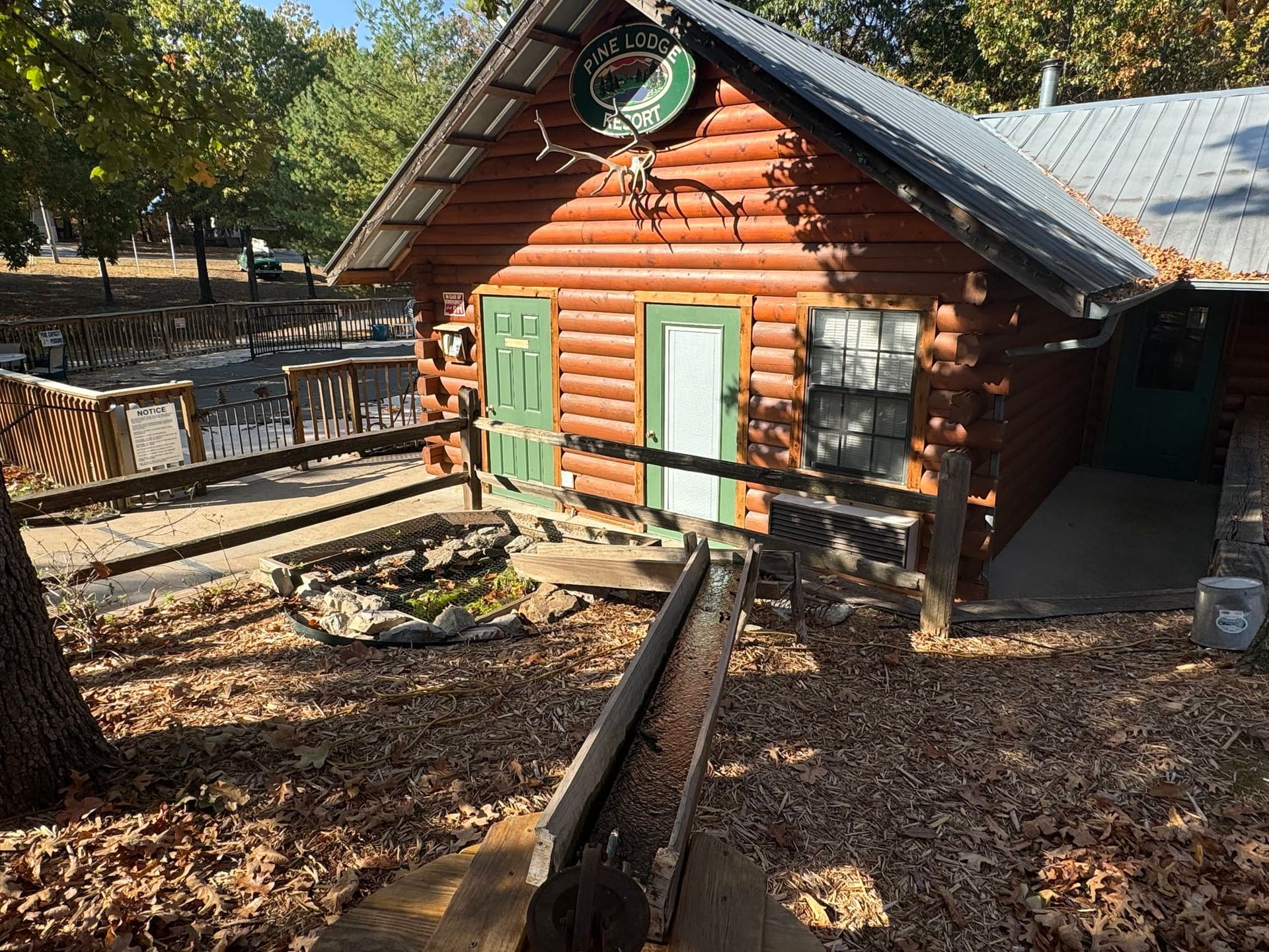 A log cabin with a green door and a fence in front of it.