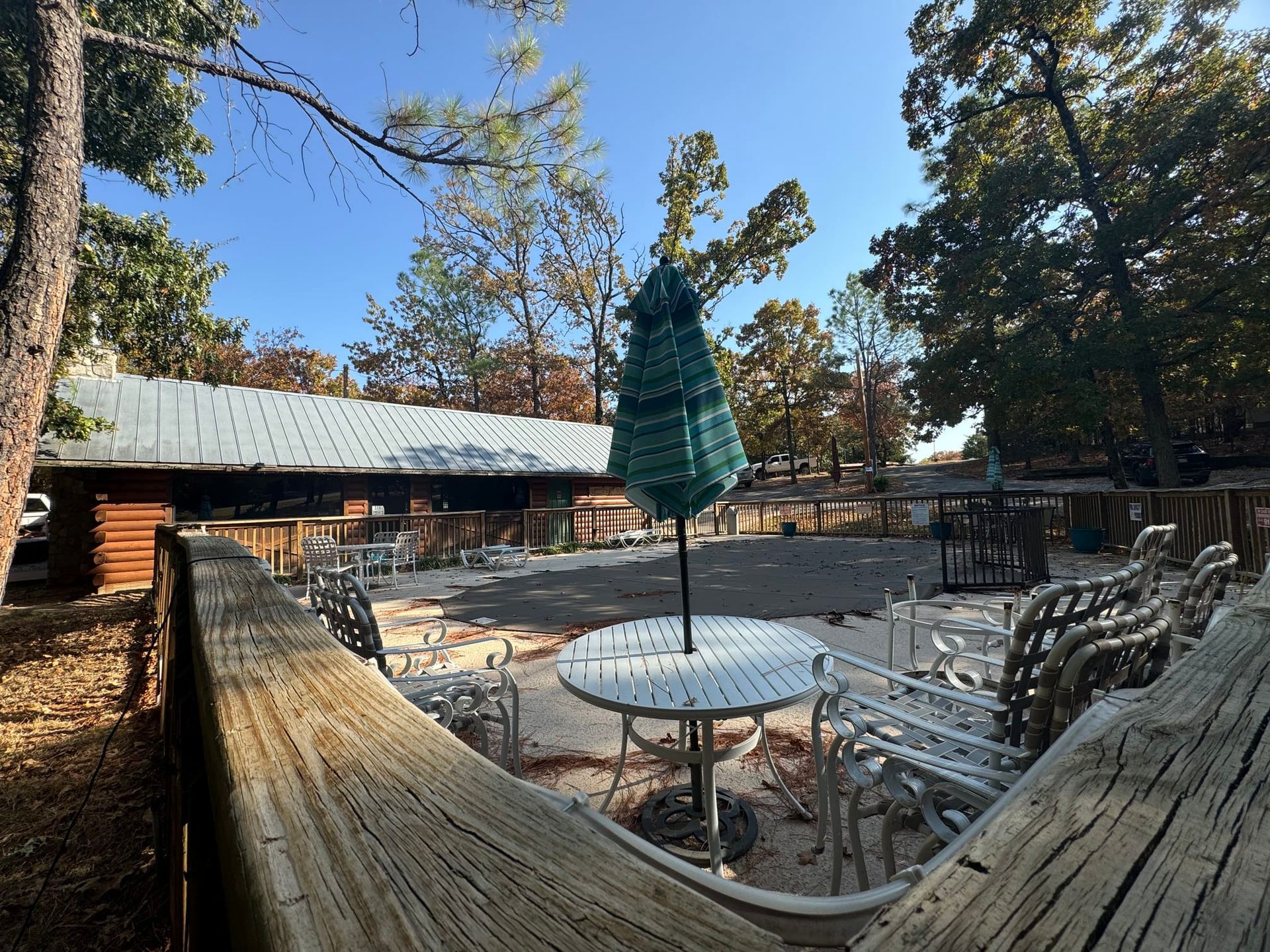 A wooden deck with a table and chairs and a green umbrella