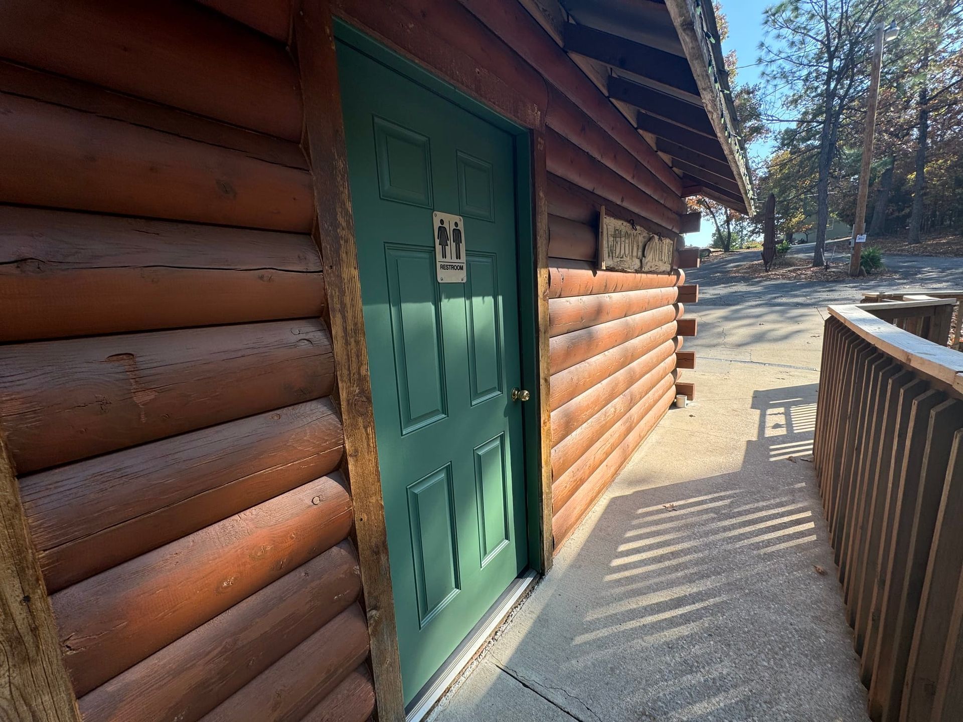 A green door is on the side of a log cabin.