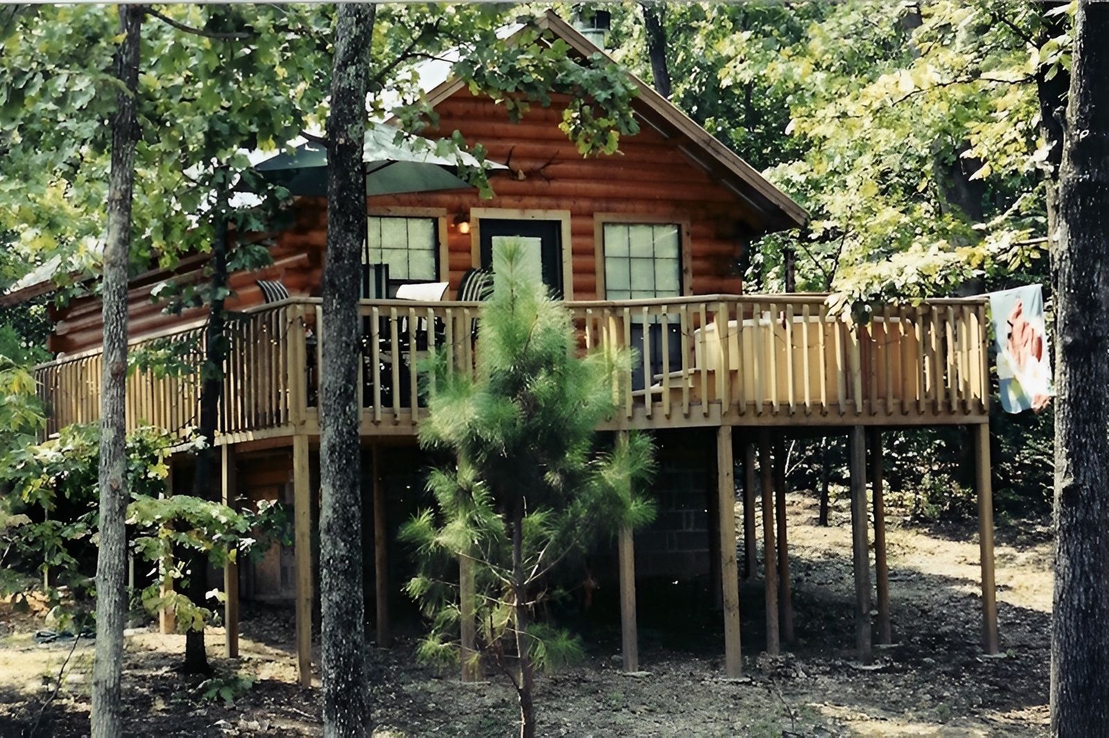 A log cabin with a large deck surrounded by trees