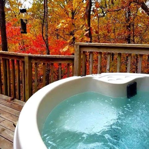 A hot tub on a deck with trees in the background