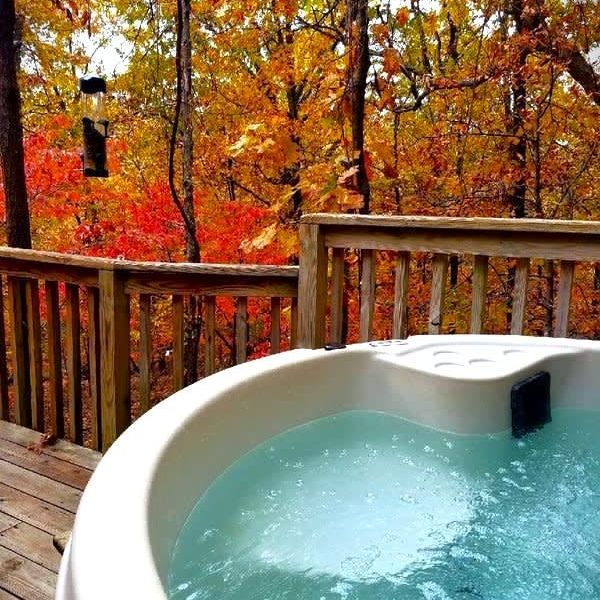 A hot tub on a deck with trees in the background