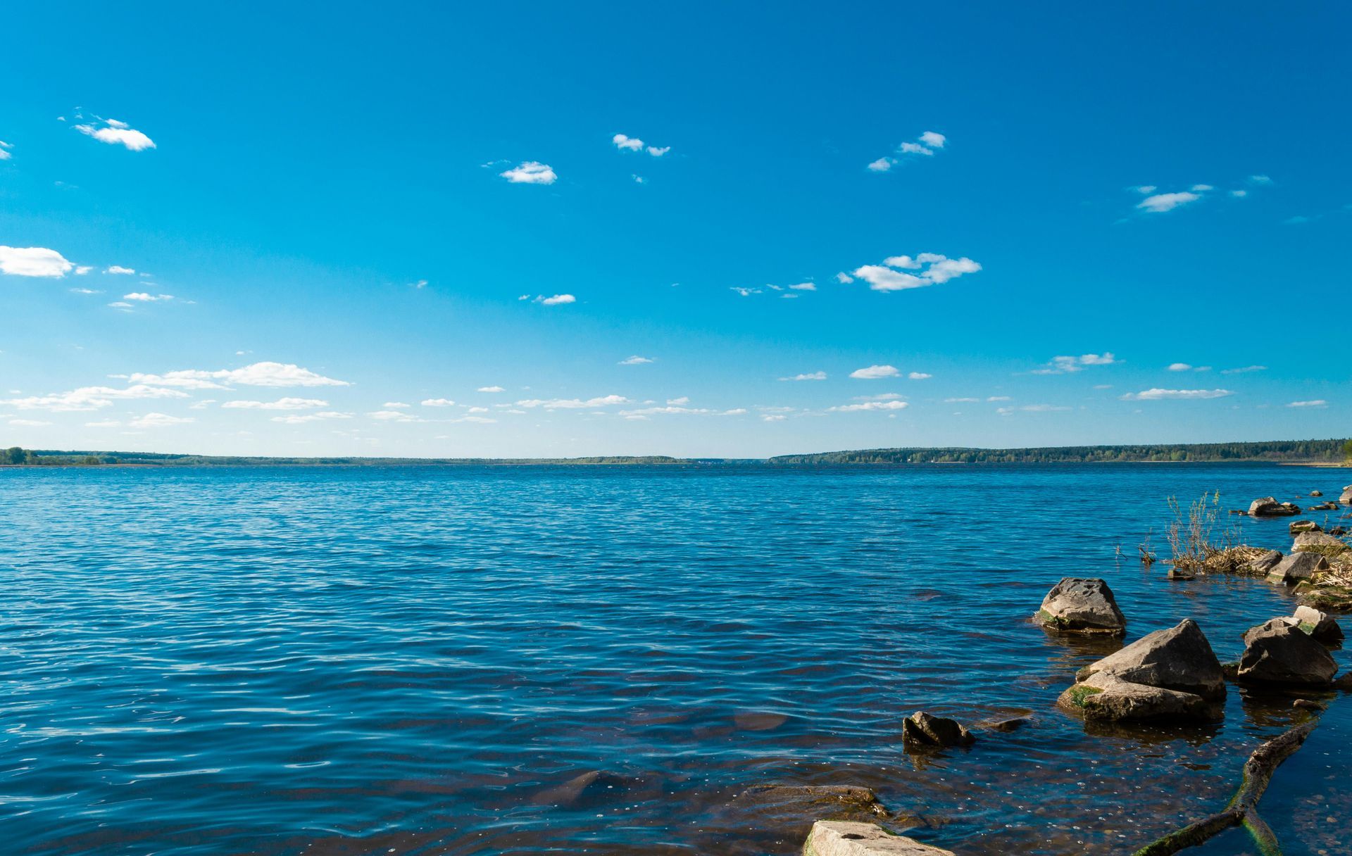 A large lake with rocks on the shore on a sunny day.