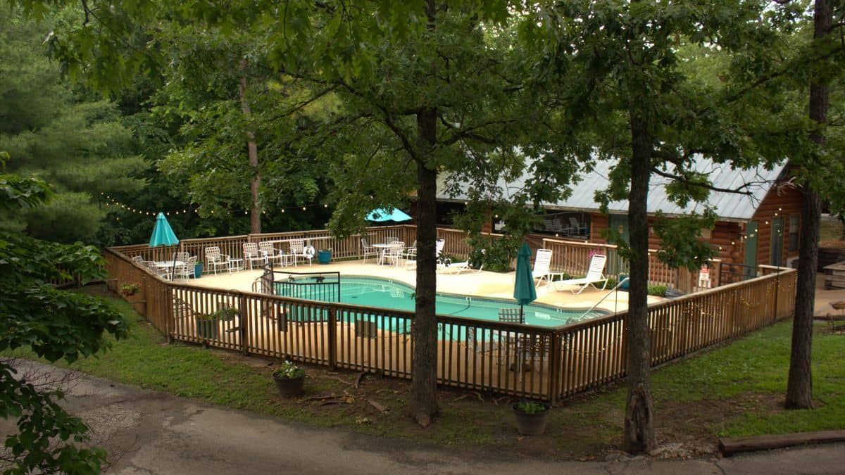 A large swimming pool surrounded by trees and a wooden fence.