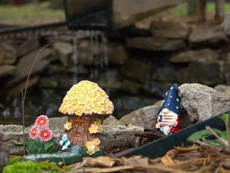A couple of gnomes standing next to each other in a fairy garden.