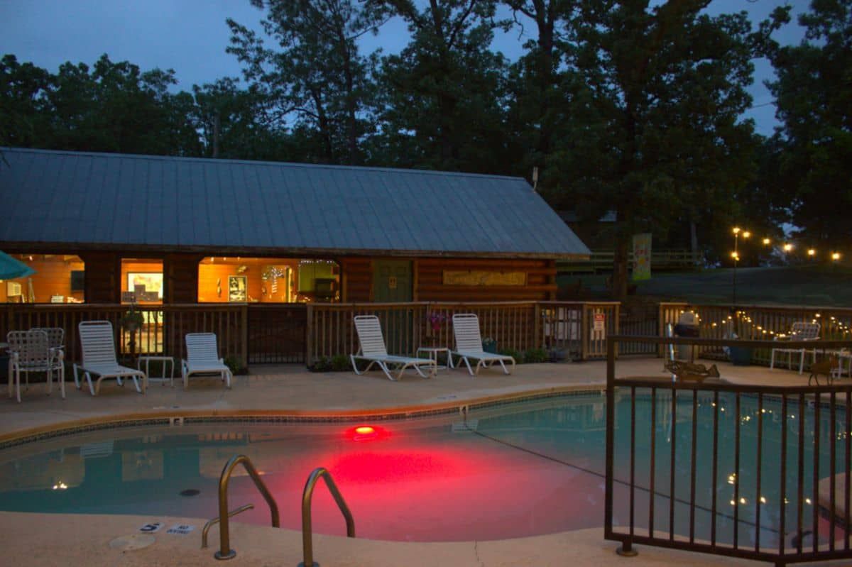 A large swimming pool is lit up at night in front of a building.