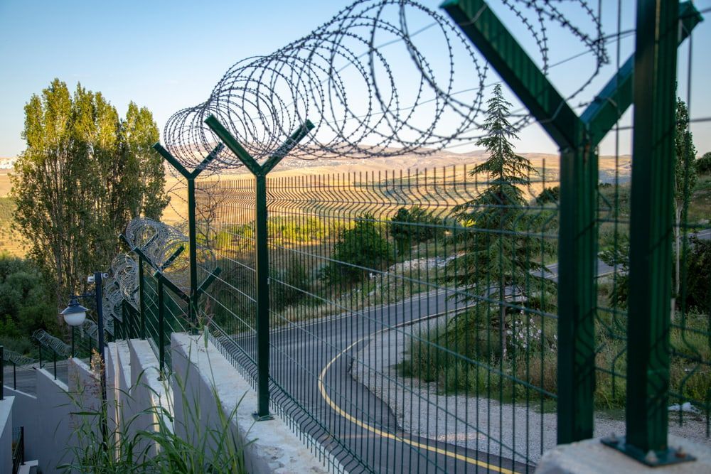 A Barbed Wire Fence Surrounds a Road With Trees in the Background — AM & JD Contracting In Muswellbrook, NSW