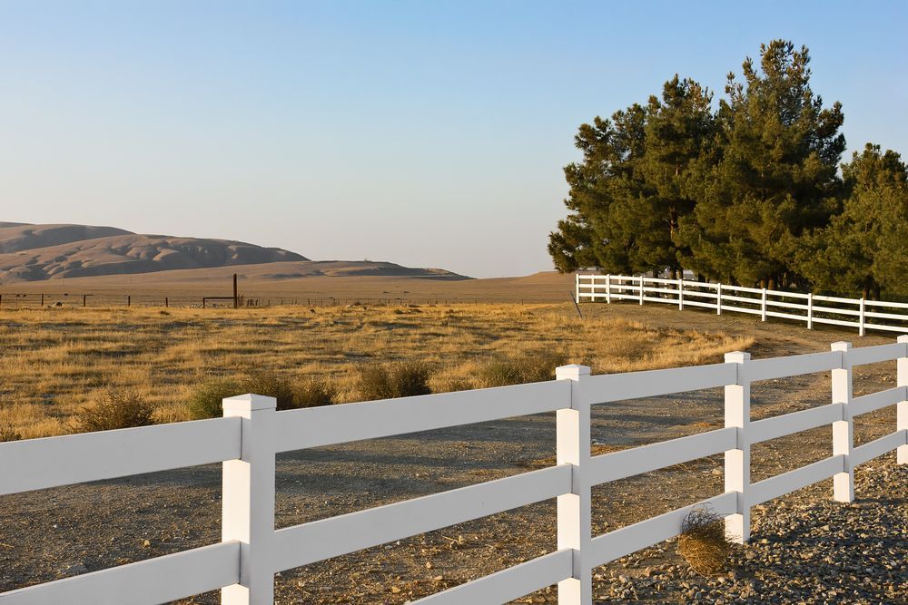 A White Fence Surrounds a Field With Mountains in the Background — AM & JD Contracting In Muswellbrook, NSW