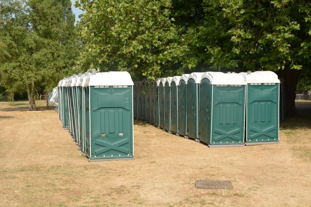A Row of Green Portable Toilets Are Lined Up in a Field — AM & JD Contracting In Muswellbrook, NSW
