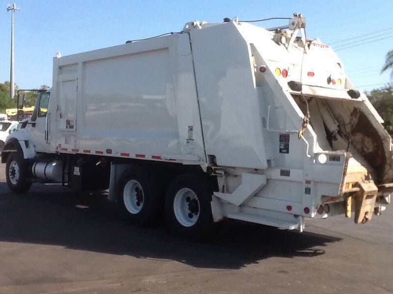 a white dumpster truck on a road