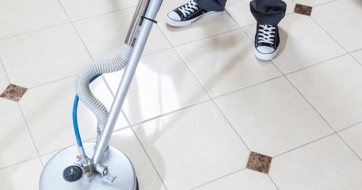 Person cleaning tile floor with a circular machine.