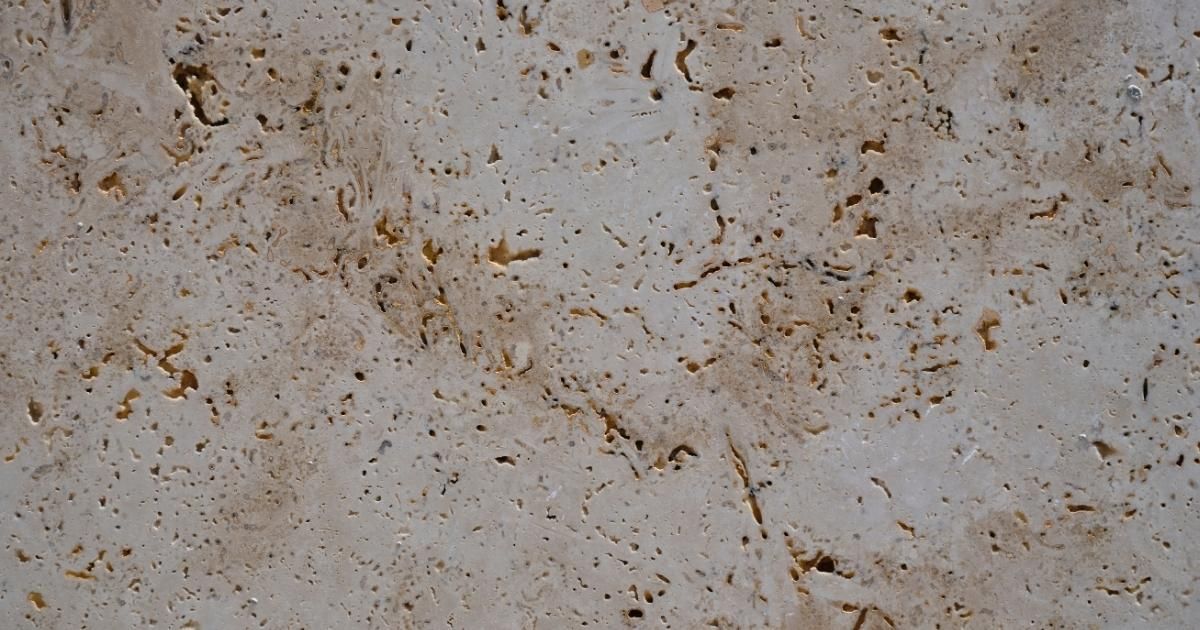 Beige and tan travertine stone surface with natural holes and veins.