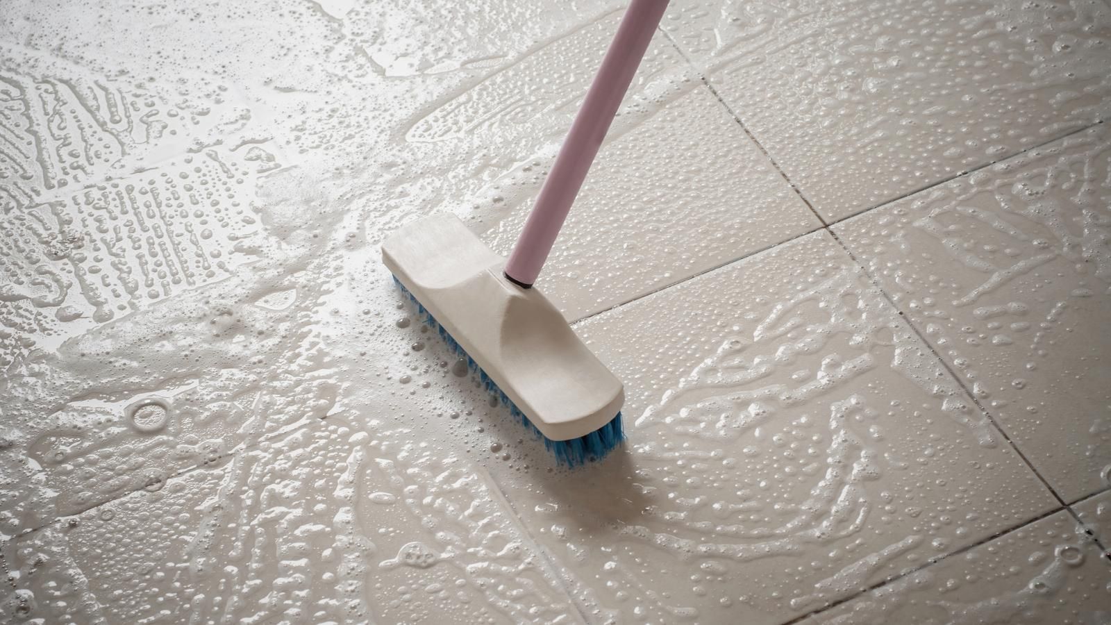 Brush scrubbing a soapy stone floor.