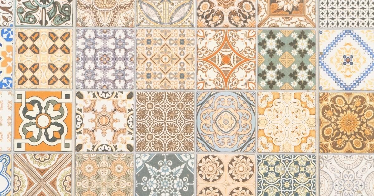 Assorted patterned ceramic tiles in muted colors arranged in a grid.