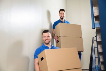 Two men are carrying boxes up a set of stairs.