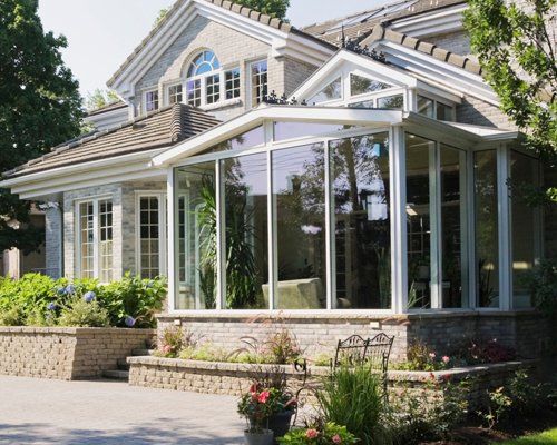 Brick and stone cottage style home with sunroom, patio and landscaped backyard