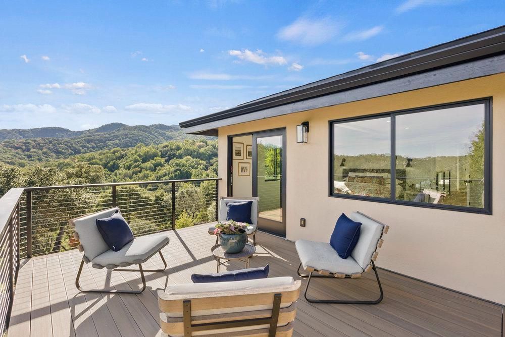 A balcony with chairs and a table with a view of the mountains.