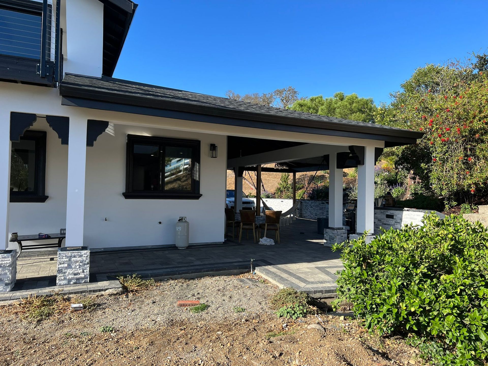 A white house with a black roof and a porch