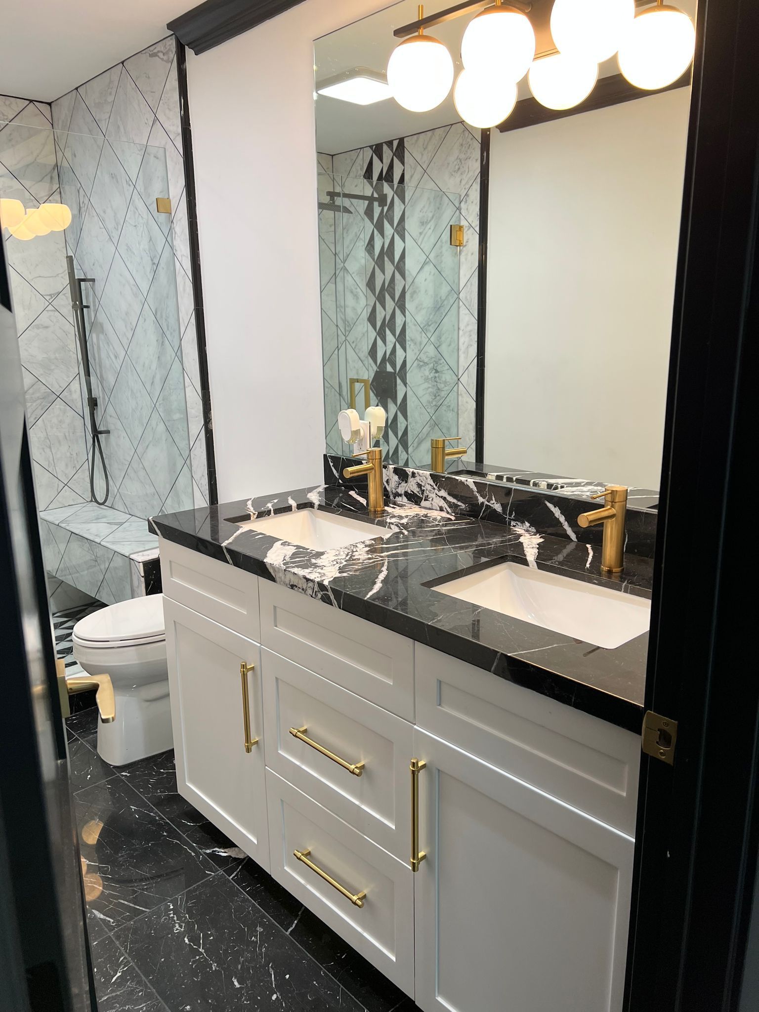 A bathroom with two sinks , a toilet and a mirror.