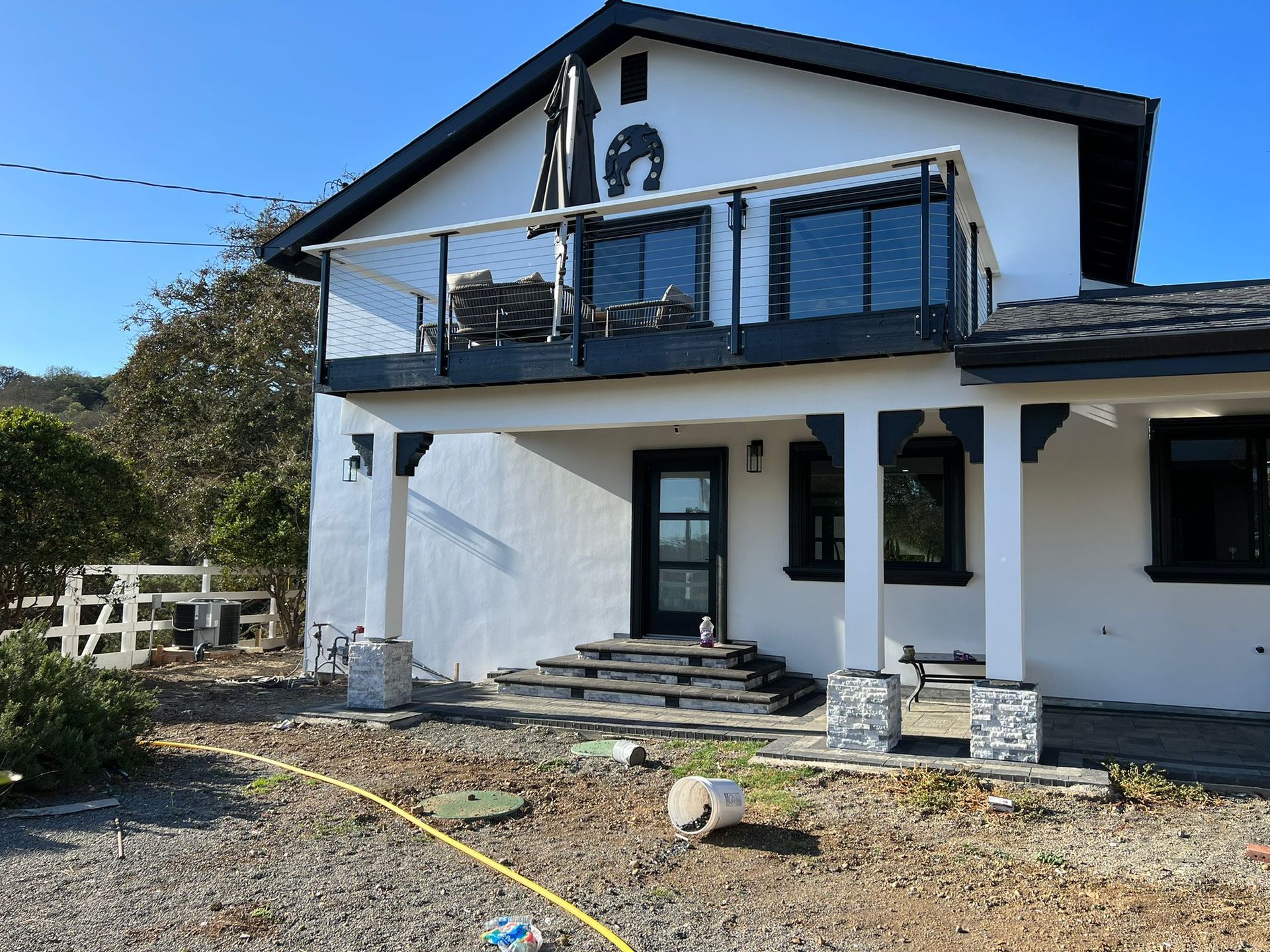 A white house with a balcony and a hose in front of it
