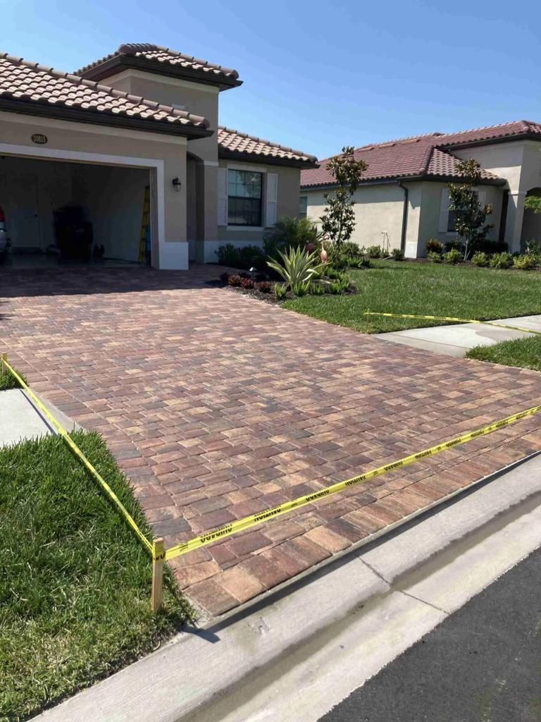 A brick driveway is being built in front of a house.