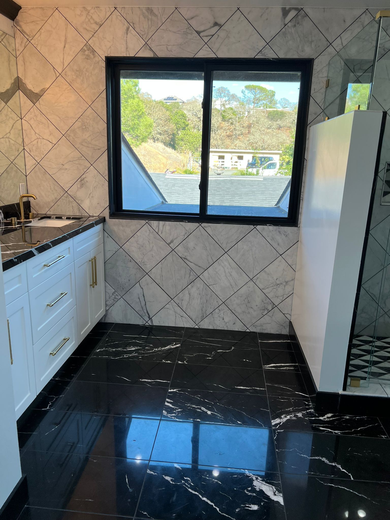 A bathroom with black and white tiles and a large window
