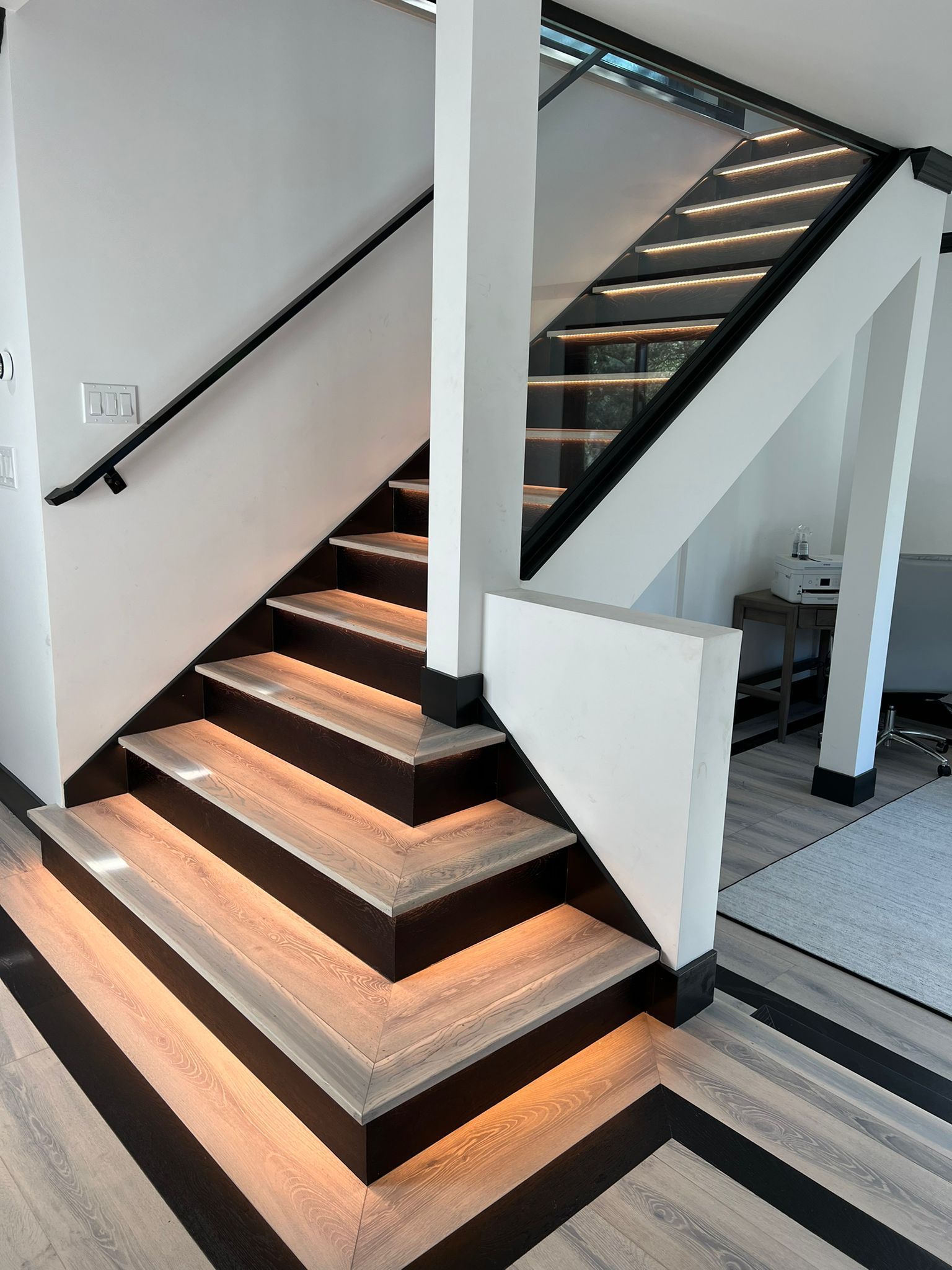 A black and white staircase with lights on the steps
