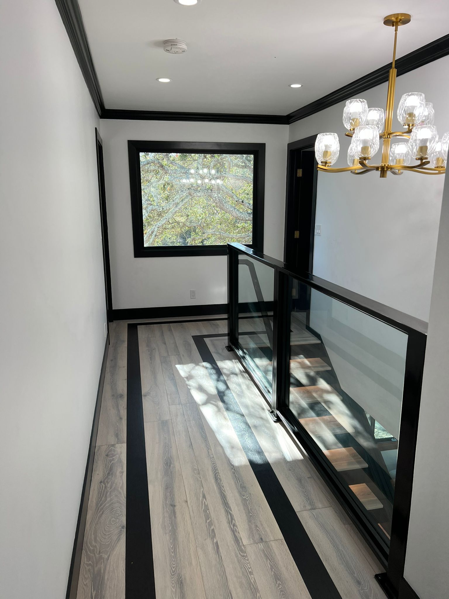 A hallway with a chandelier hanging from the ceiling and a window.