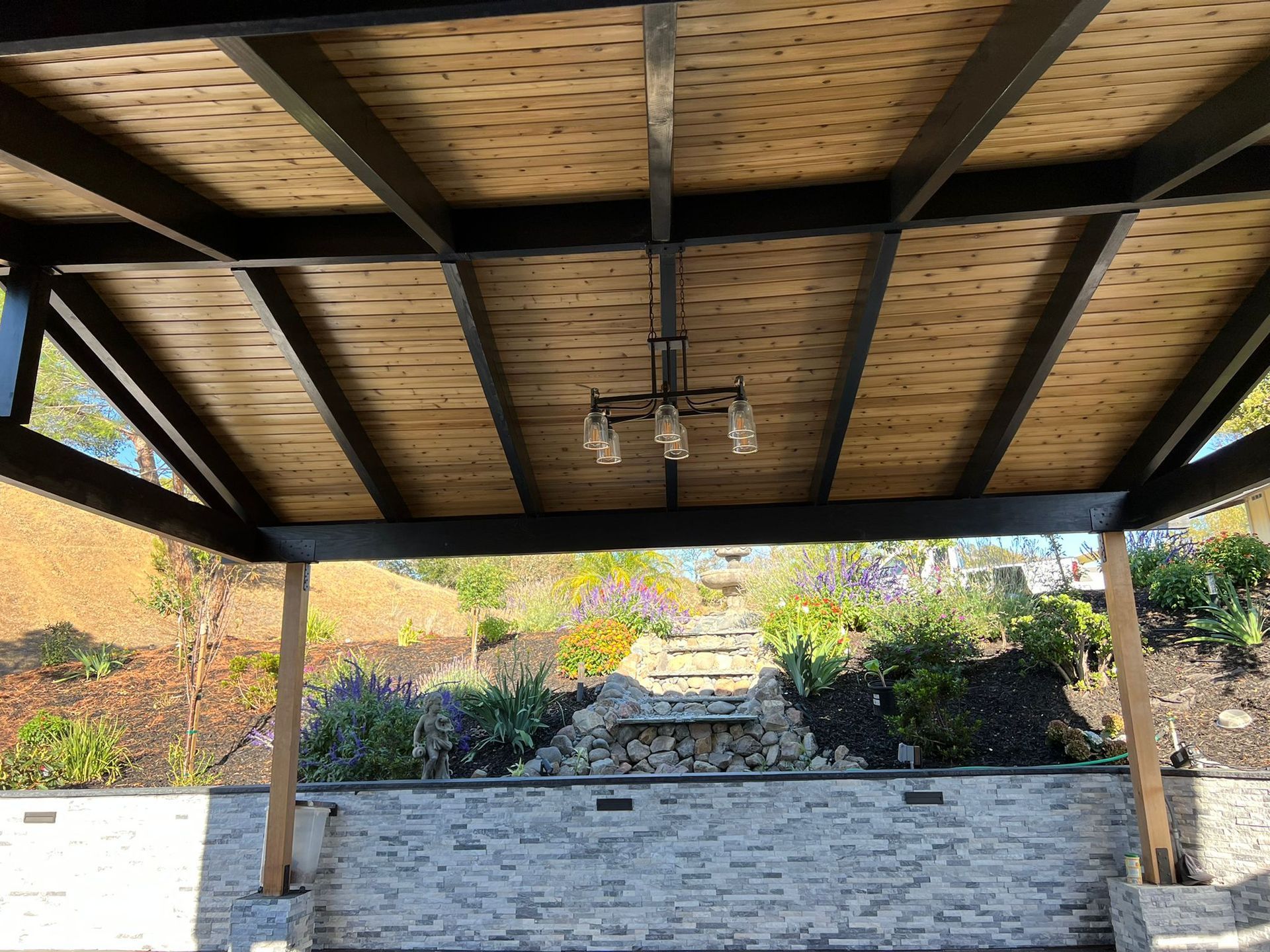 A wooden gazebo with a chandelier hanging from the ceiling.