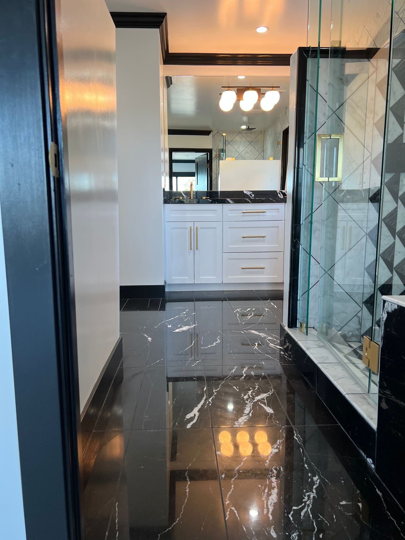 A bathroom with black marble floors and white cabinets