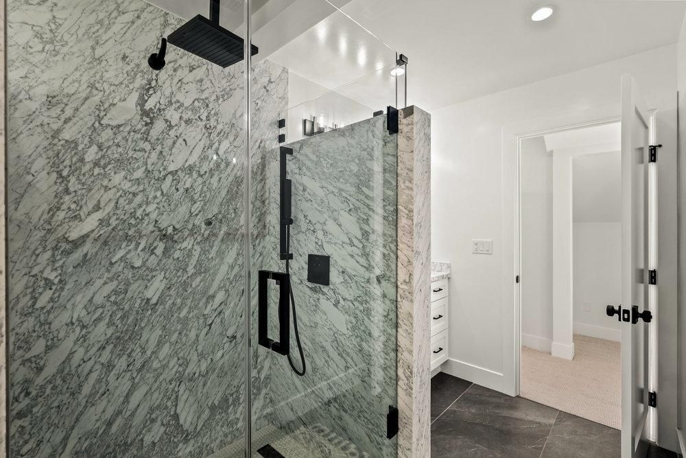 A bathroom with a walk in shower and a black shower head.