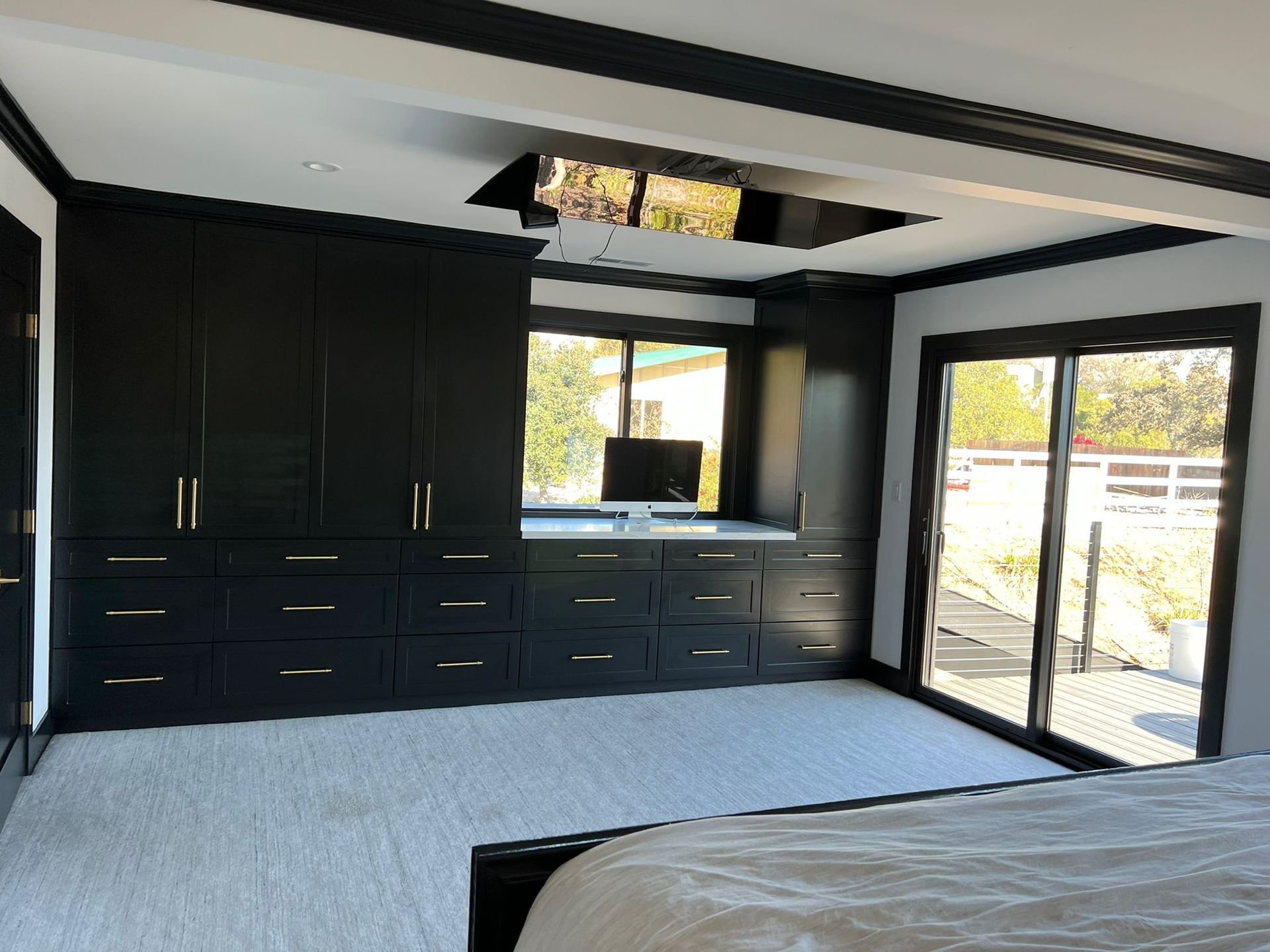 A bedroom with a large bed and lots of black cabinets