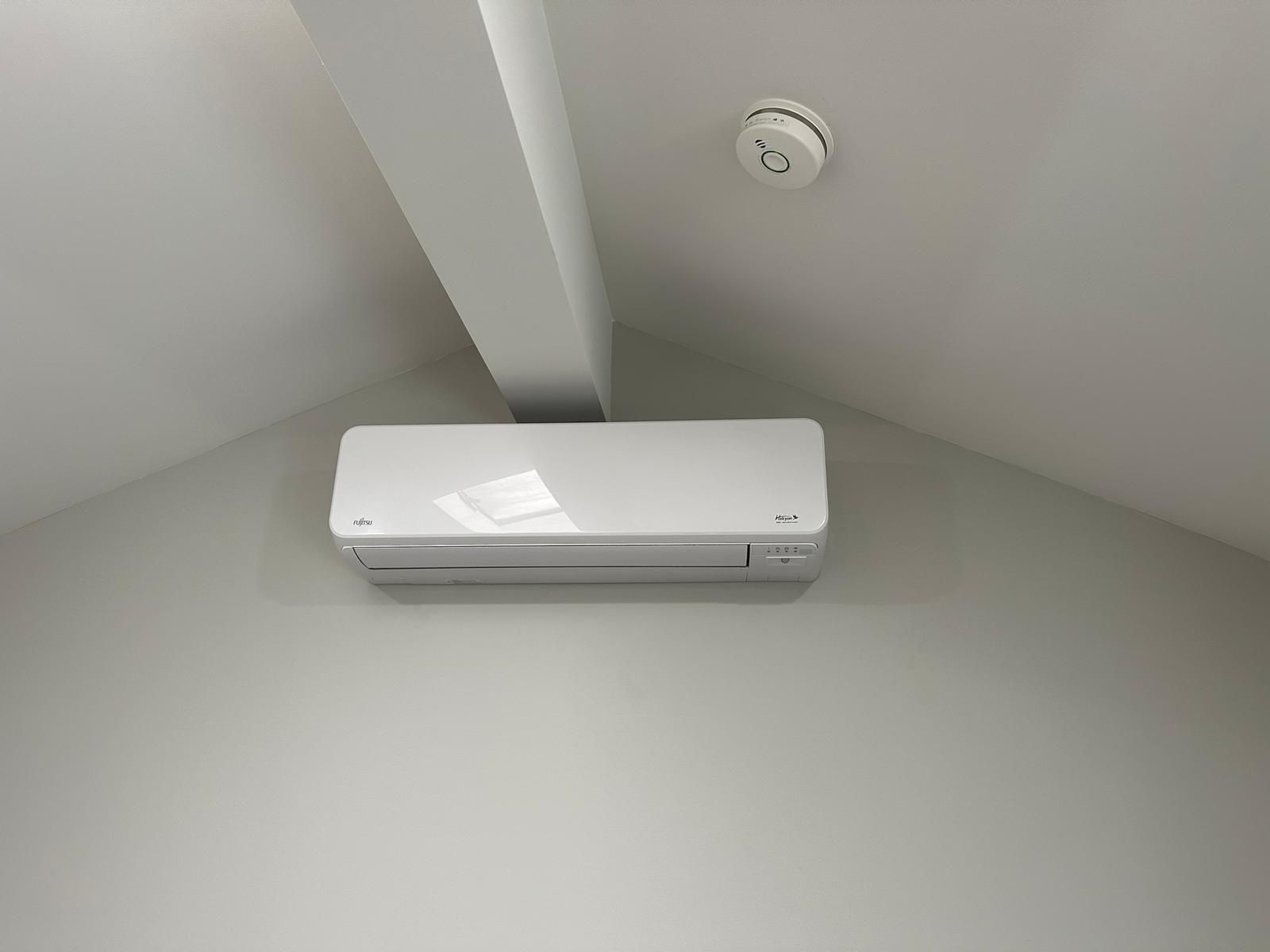 A white air conditioner is hanging from the ceiling in a room.