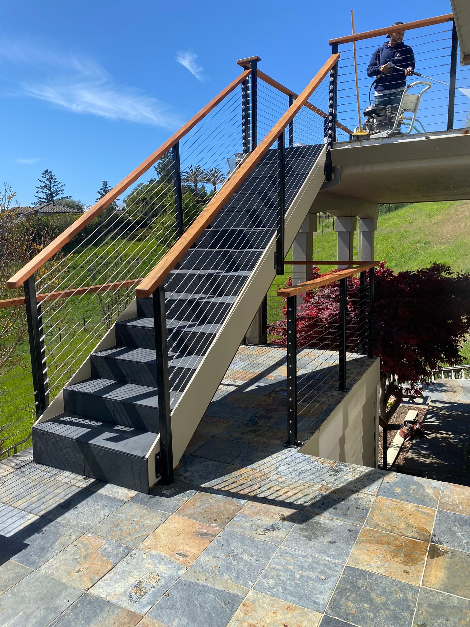 A man in a wheelchair is sitting on a balcony overlooking a staircase.