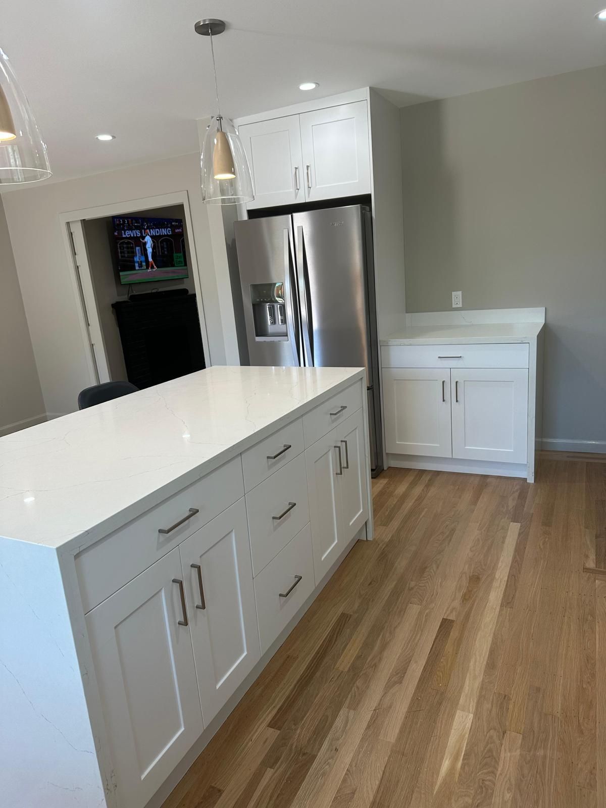 A kitchen with white cabinets , stainless steel appliances , and hardwood floors.