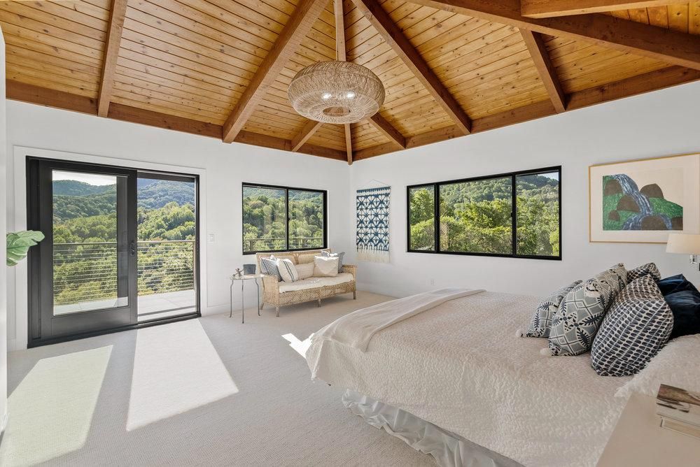 A bedroom with a bed , couch , and lots of windows.