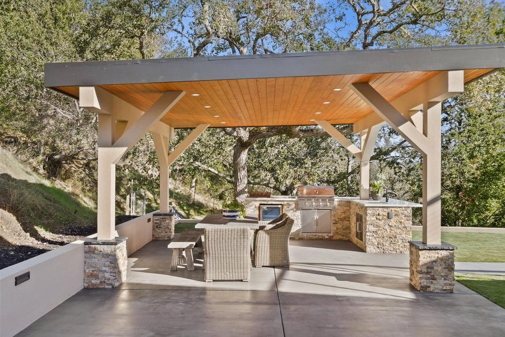 There is a large outdoor kitchen under a pergola.