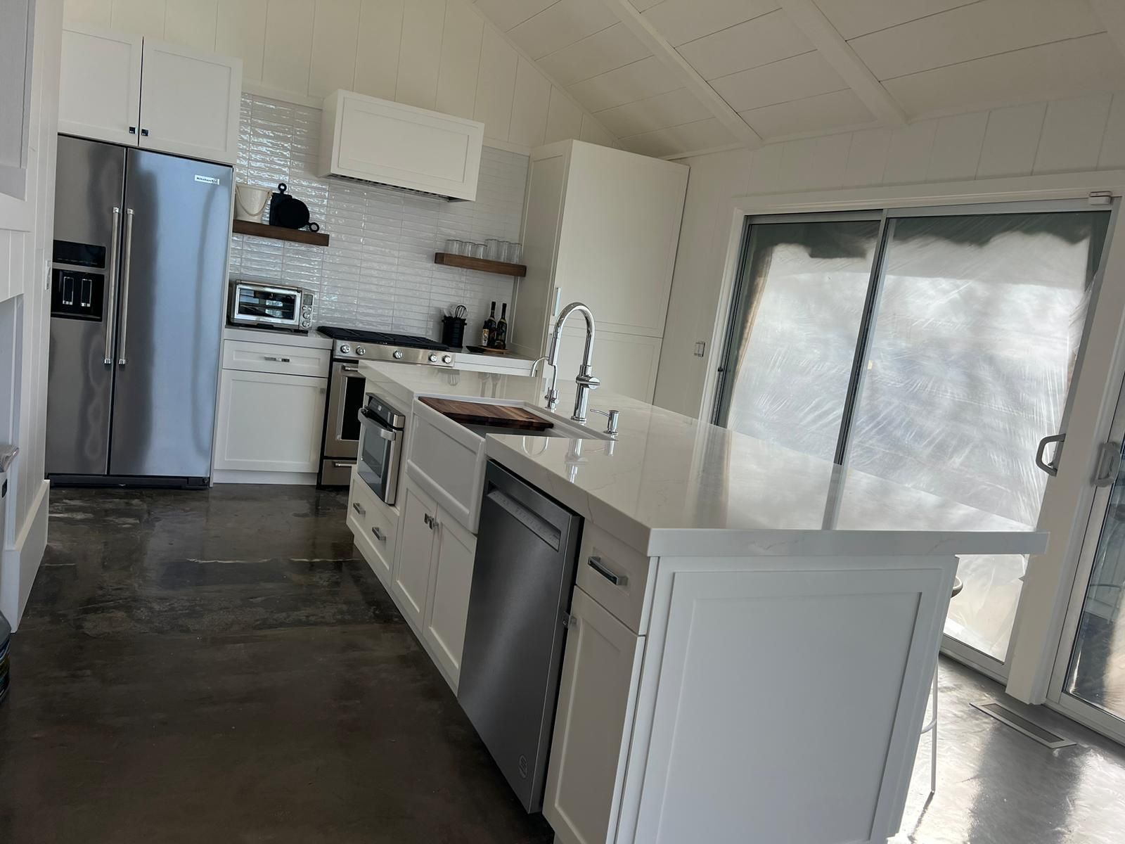A kitchen with white cabinets , stainless steel appliances and a large island.