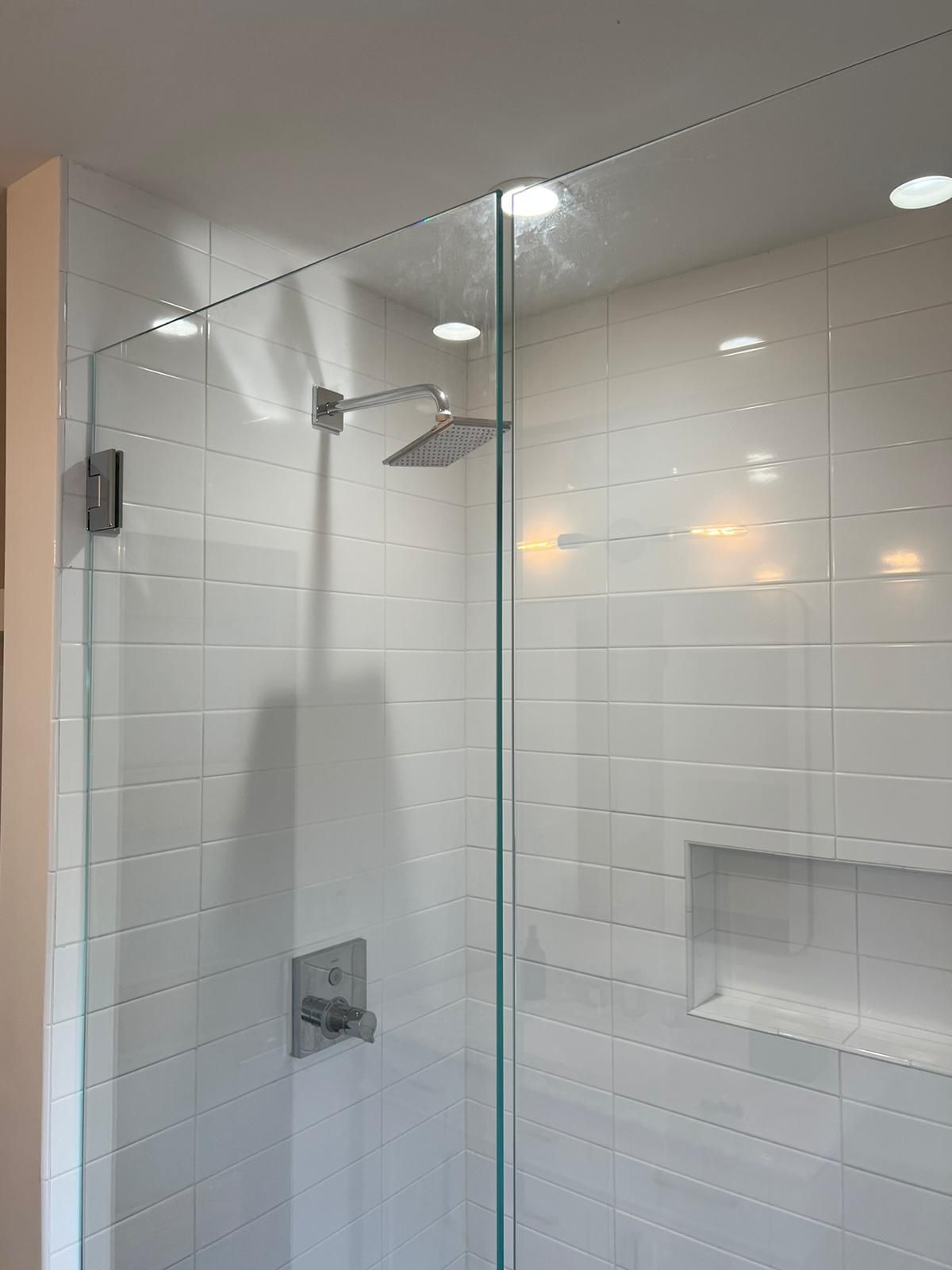 A shower with a glass door and a shower head.