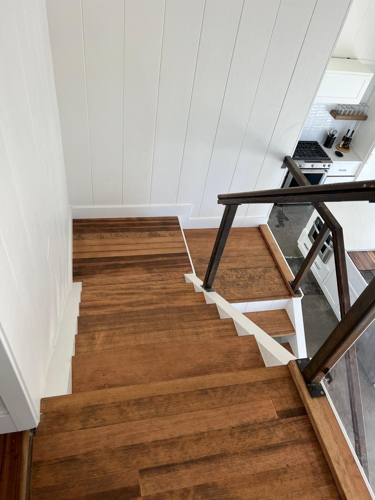 A wooden staircase with a white railing leading to a kitchen.