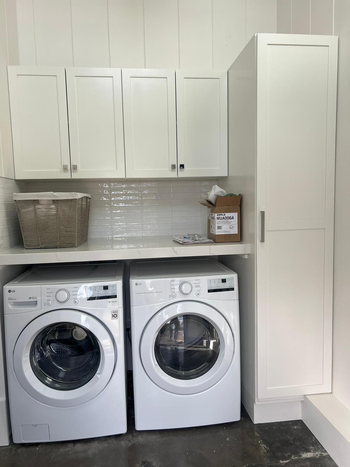 A laundry room with two washing machines and a dryer.