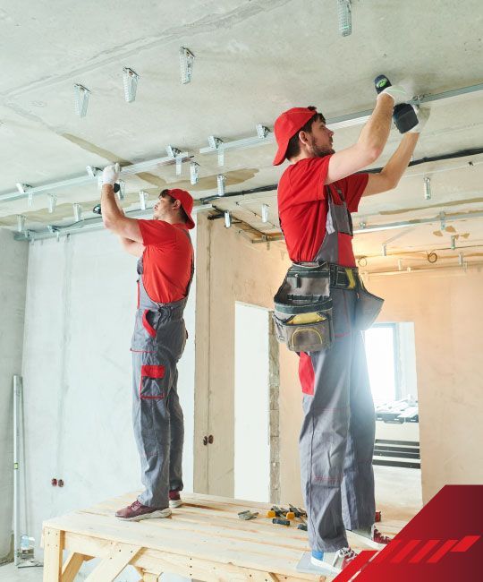 Two men are working on a ceiling in a room.