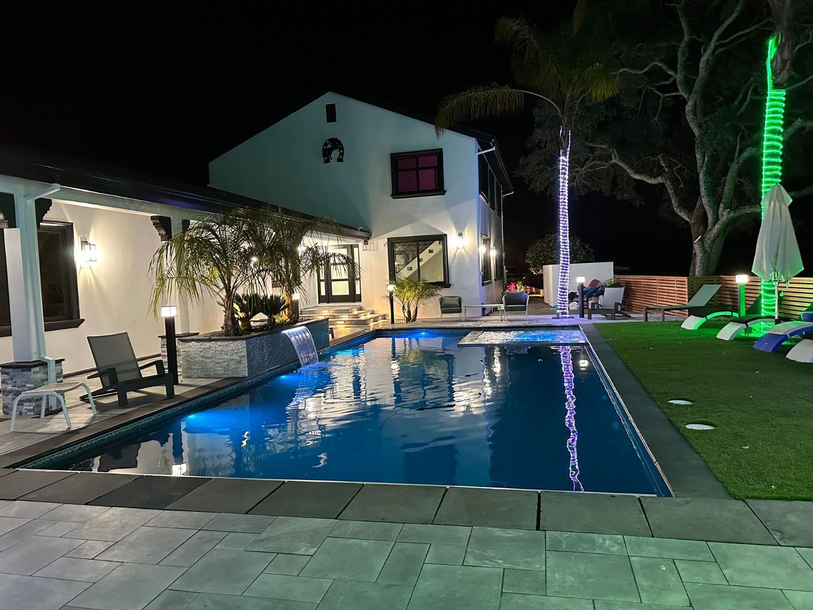 A large swimming pool in front of a house at night
