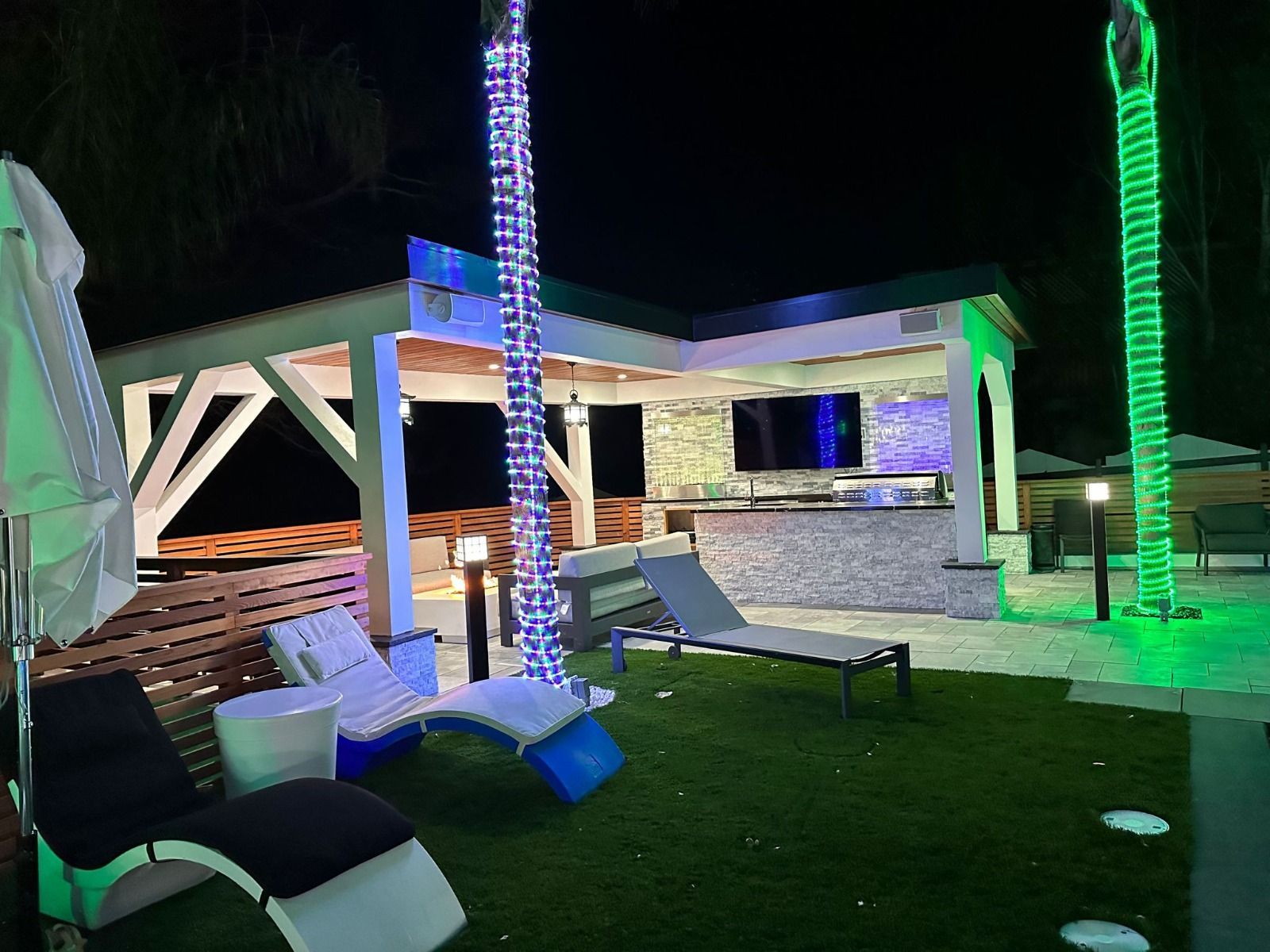 A patio area with chairs and umbrellas at night