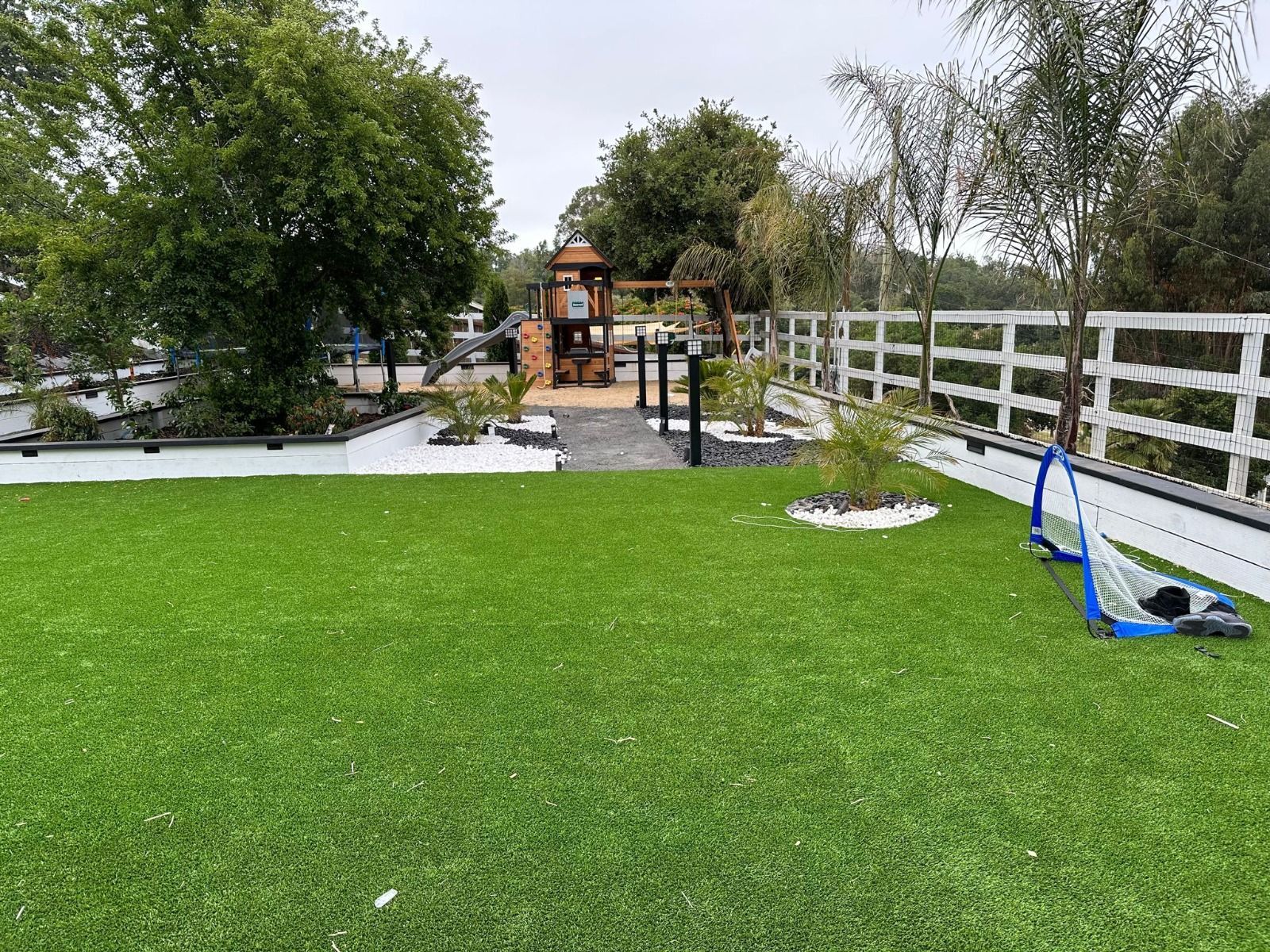A large lush green lawn with a playground in the background.