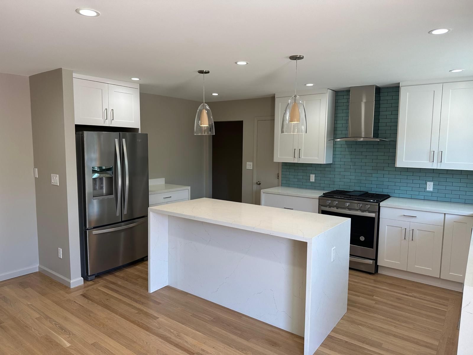 A kitchen with white cabinets , stainless steel appliances , and a large island.