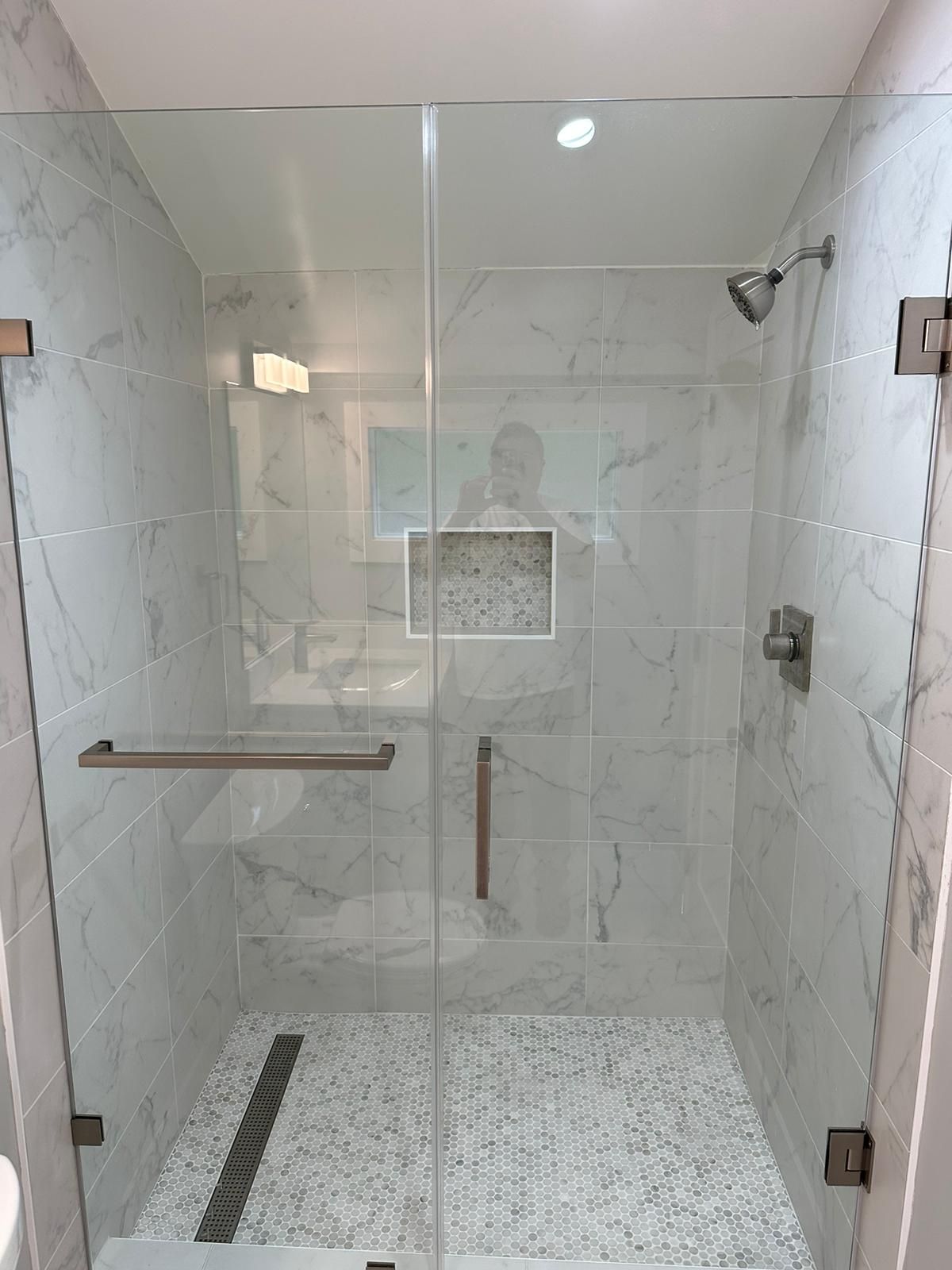 A bathroom with a walk in shower with a glass door.