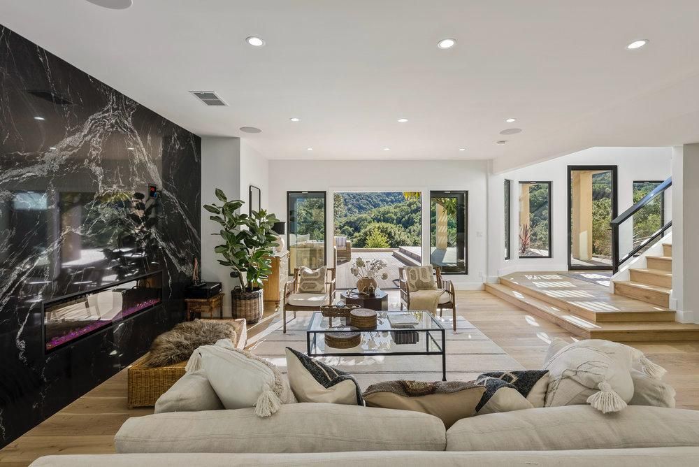 A living room with a couch , chairs , coffee table and television.