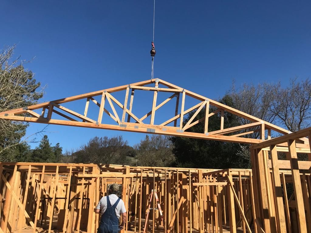 A man is standing in front of a wooden structure under construction.