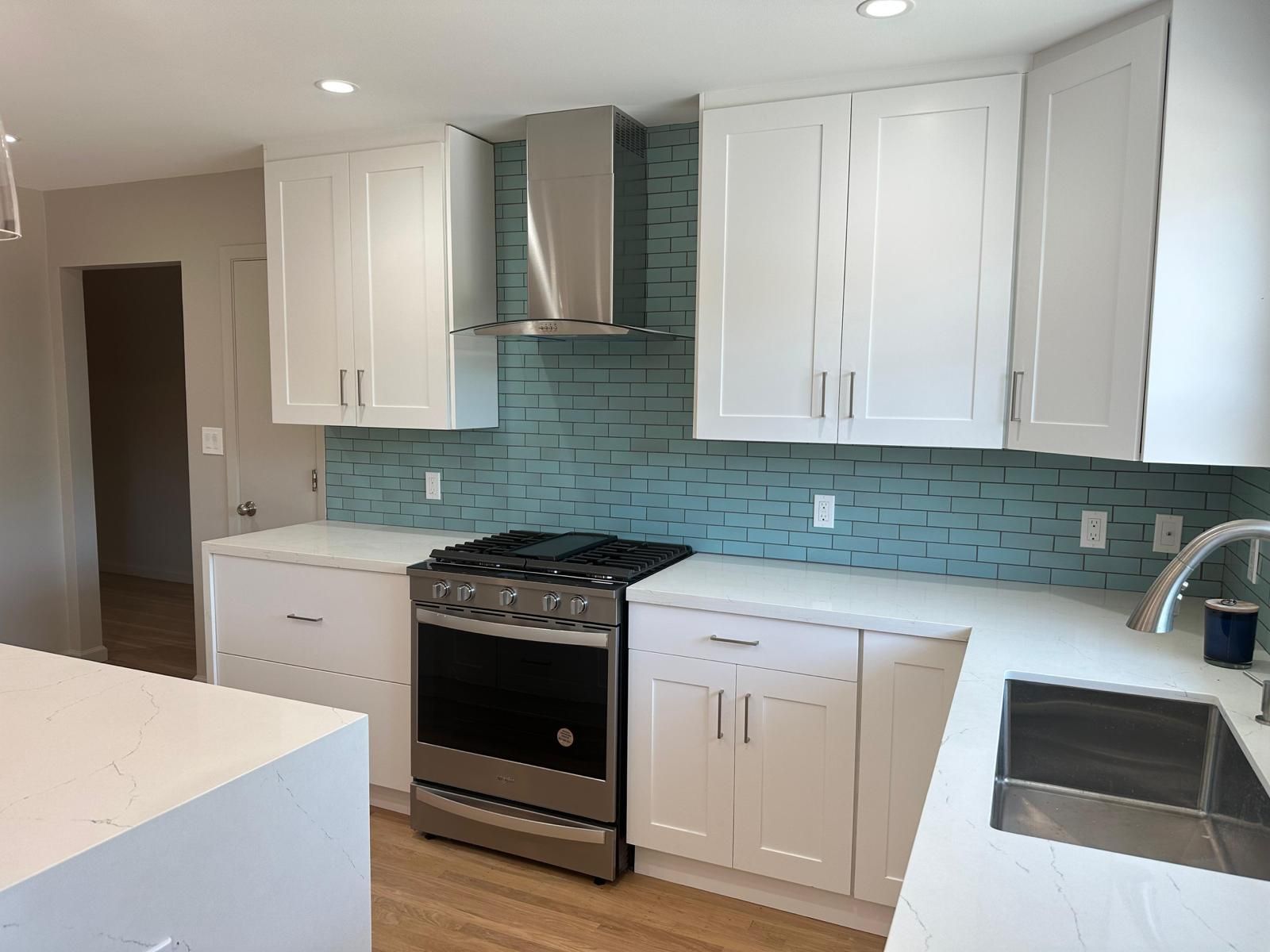 A kitchen with white cabinets , a stove , and a sink.
